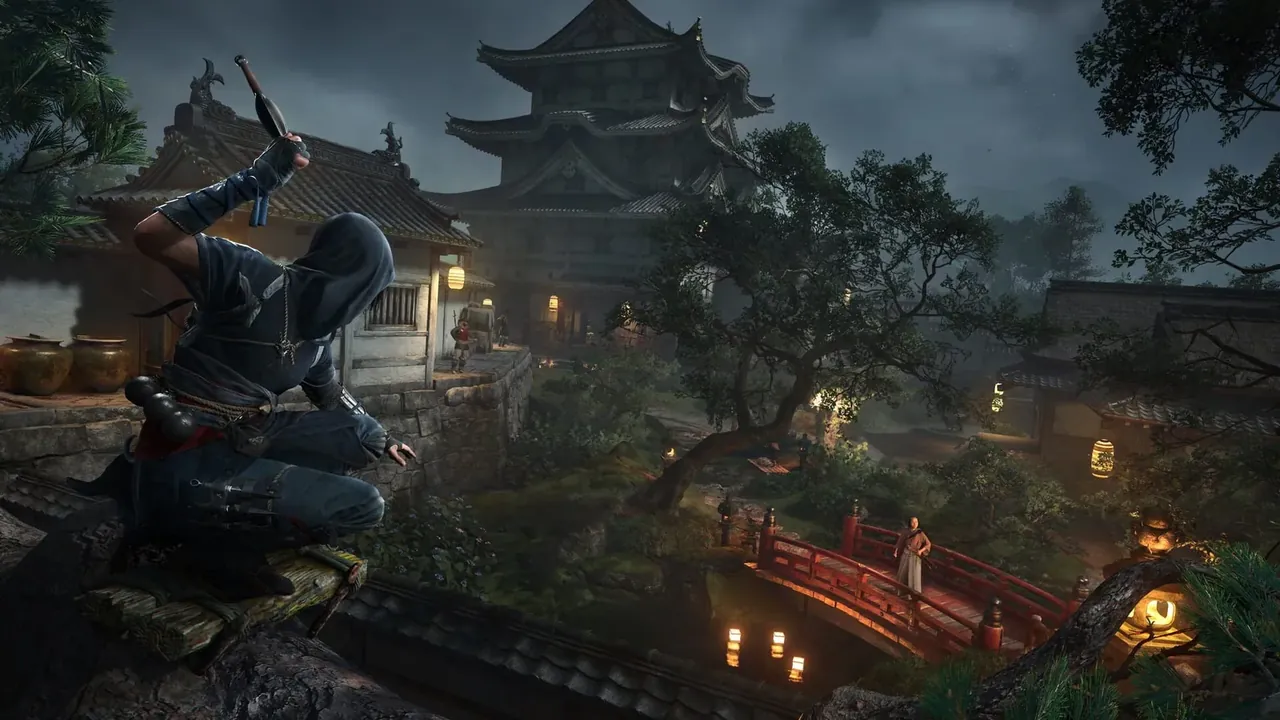 Naoe accroupie sur un toit, au-dessus d'un village japonais éclairé aux lanternes dans Assassin's Creed Shadows
