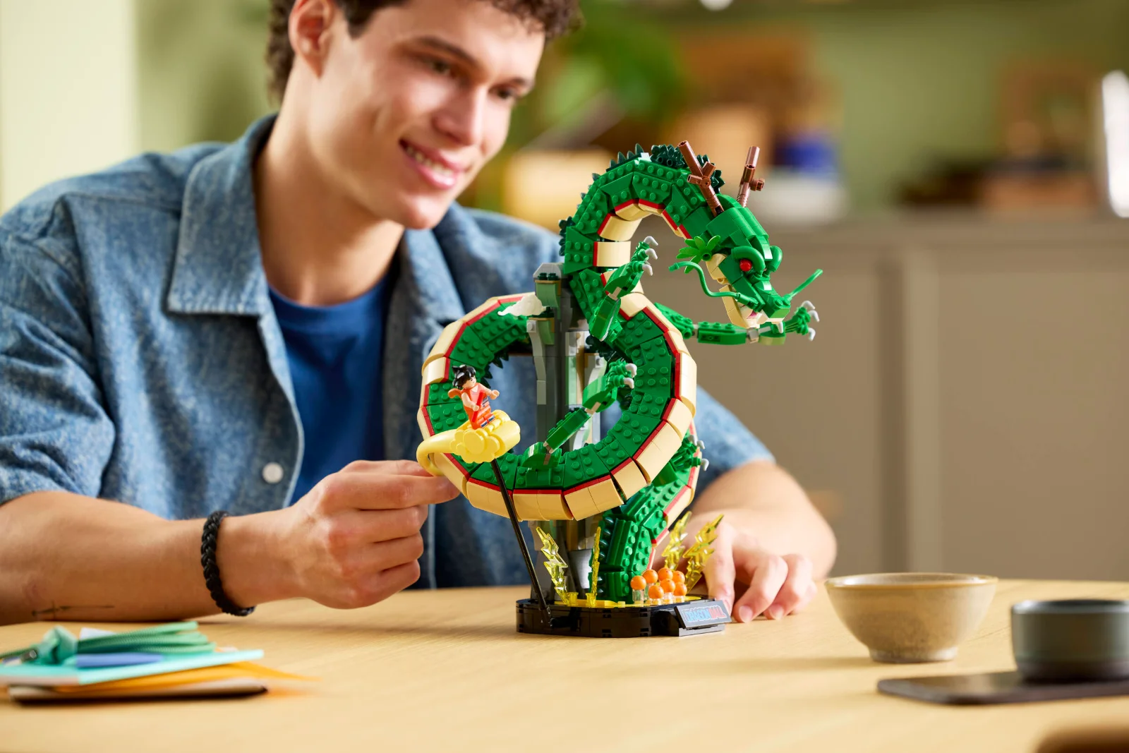 Un adulte construit le set LEGO Dragon Ball Shenron et Goku, dragon vert terminé devant lui