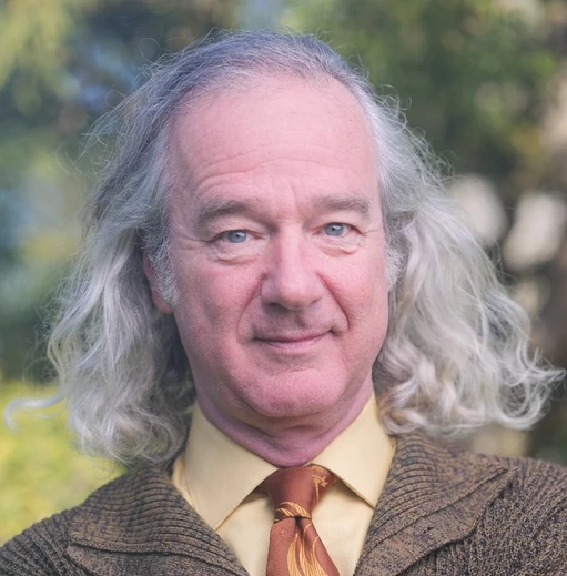 Portrait de Jeffrey Weissman, cheveux gris longs, cardigan marron et cravate orange