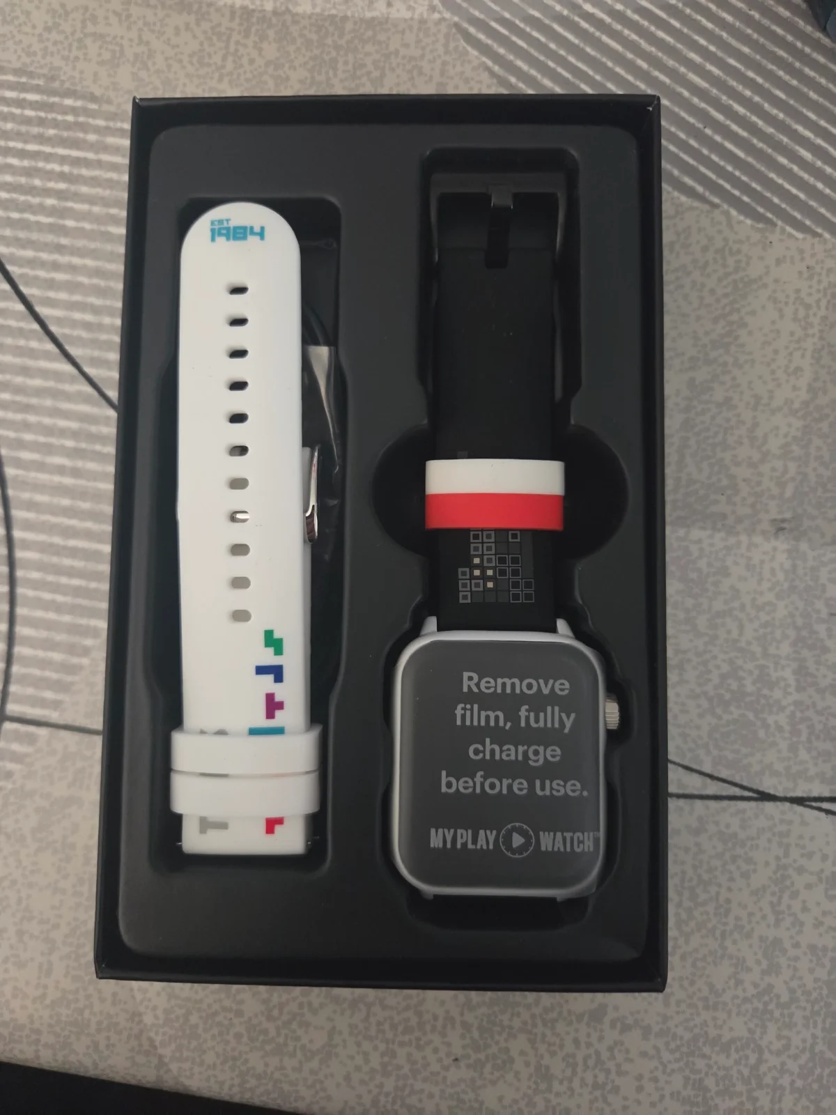 Le contenu de la boîte de la My Play Watch Tetris, avec la montre et le bracelet blanc de rechange