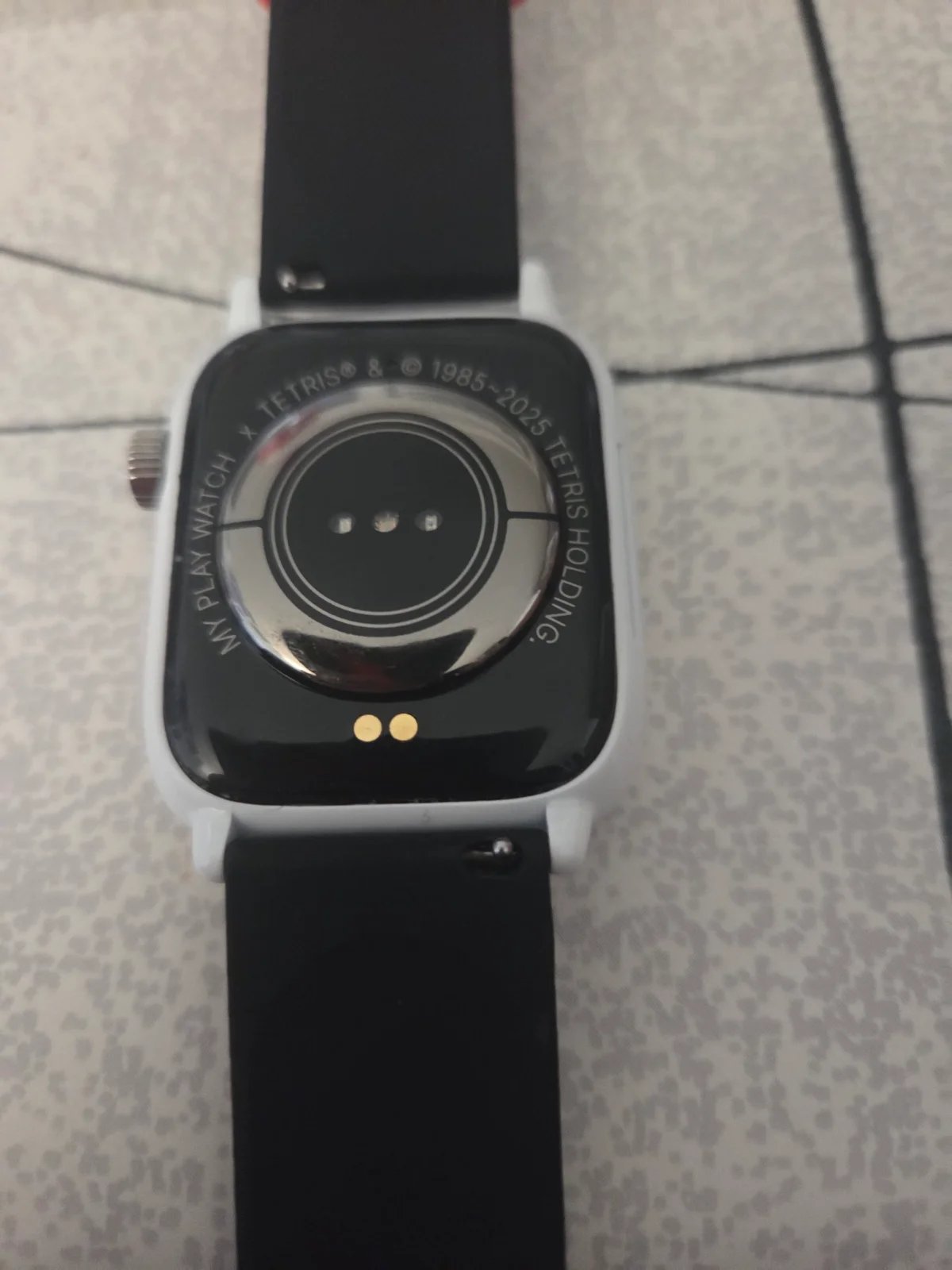Le dos de la My Play Watch Tetris, avec le capteur cardiaque et les deux contacts de recharge
